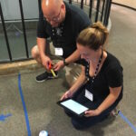 People recording measurements of the position of a ball on the floor
