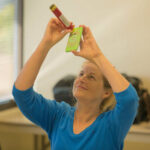 Woman viewing through her smartphone an image shown through a mini telescope held up to her smartphone for MADE Science
